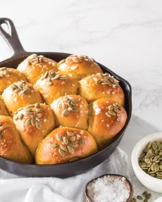 a pan filled with rolls covered in pumpkin seeds