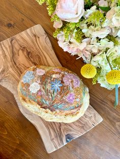 a cake sitting on top of a wooden table next to flowers