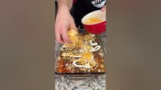 someone is adding cheese to the casserole dish