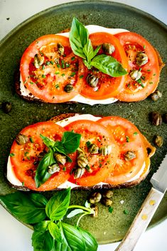 two slices of bread topped with tomatoes and pesto on top of a green plate