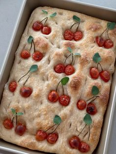 an uncooked pizza with cherry tomatoes and basil on top, in a pan