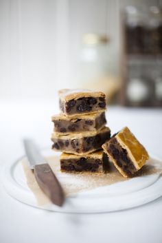 four pieces of cake sitting on top of a white plate next to a knife and fork