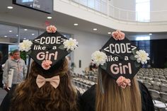 two girls wearing graduation caps with flowers on their hats that say code like a girl
