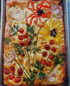 a square pizza with tomatoes, onions and herbs on it