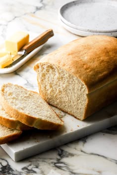 a loaf of bread sitting on top of a cutting board next to butter and cheese