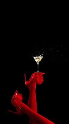 a woman in red dress holding a martini glass with liquid pouring out of the top