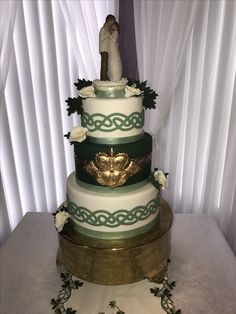 a three tiered wedding cake decorated with white flowers and greenery on a table