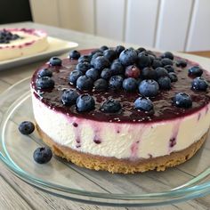a cheesecake topped with blueberries on top of a glass plate