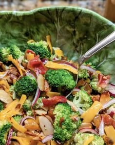 a salad with broccoli, onions and cheese is in a bowl on the table