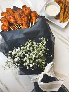 chicken skewers and flowers on a table with dipping sauce
