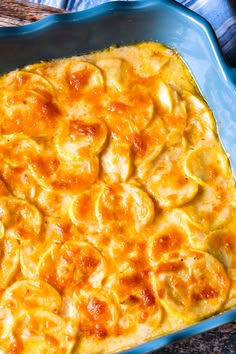 a casserole dish in a blue baking dish on a wooden table with utensils