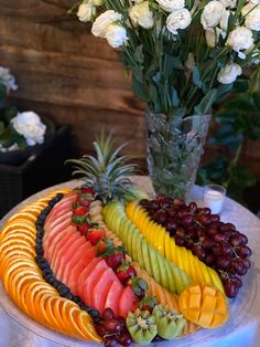 a platter filled with fruit and flowers on top of a table