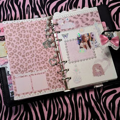 a pink and black zebra print binder with an open book on top of it