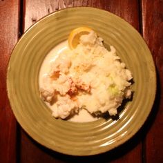 a plate full of mashed potatoes and lemon wedges on a wooden table top