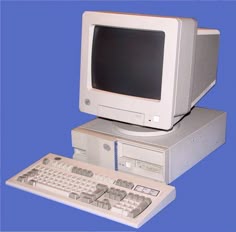 an old computer sitting on top of a desk next to a keyboard and mouse in front of a blue background