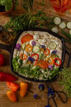 a pan filled with vegetables sitting on top of a wooden table next to sliced cucumbers