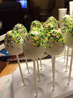 cake pops with green and yellow sprinkles are on a white platter