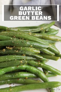 garlic butter green beans on a white plate with seasoning sprinkled over them