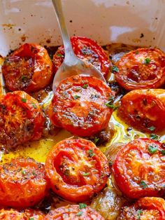 cooked tomatoes in a casserole dish with a spoon resting on the top one
