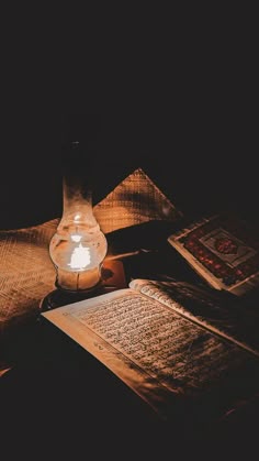 an open book sitting on top of a wooden table next to a candle and some books