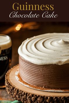 a chocolate cake with white frosting sitting on top of a wooden plate next to a mug