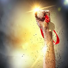 a hand with a red ribbon on it holding up a lightbulb in the air