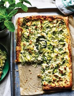 there is a square pizza on the pan with one slice cut out and another half eaten