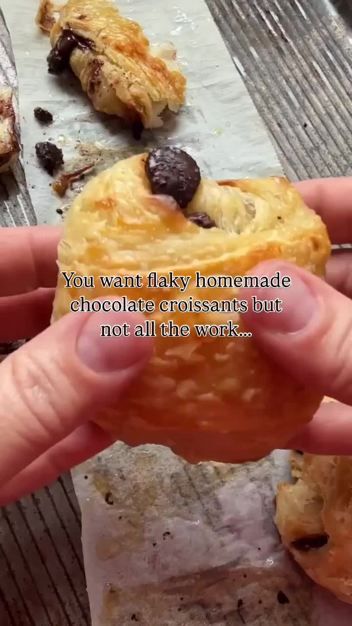 This may contain: someone is holding a half eaten chocolate chip cookie in their left hand, with the words you want dark homemade chocolate croissants but not all the work