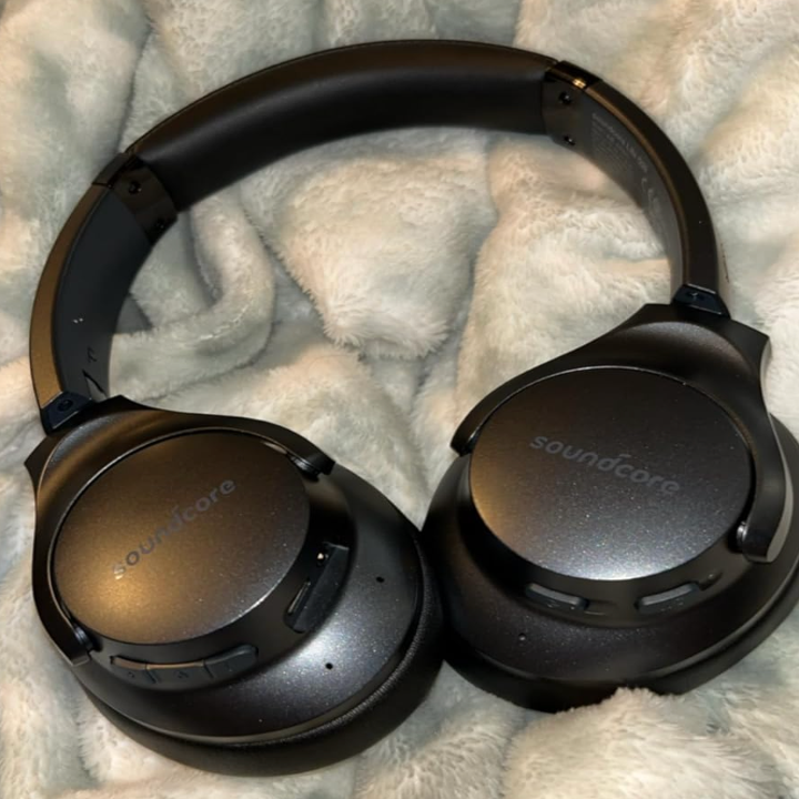 Black over-ear headphones resting on a soft, textured surface