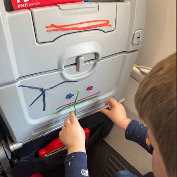 Child playing with colorful Wikki Stix, arranging designs on an airplane tray table