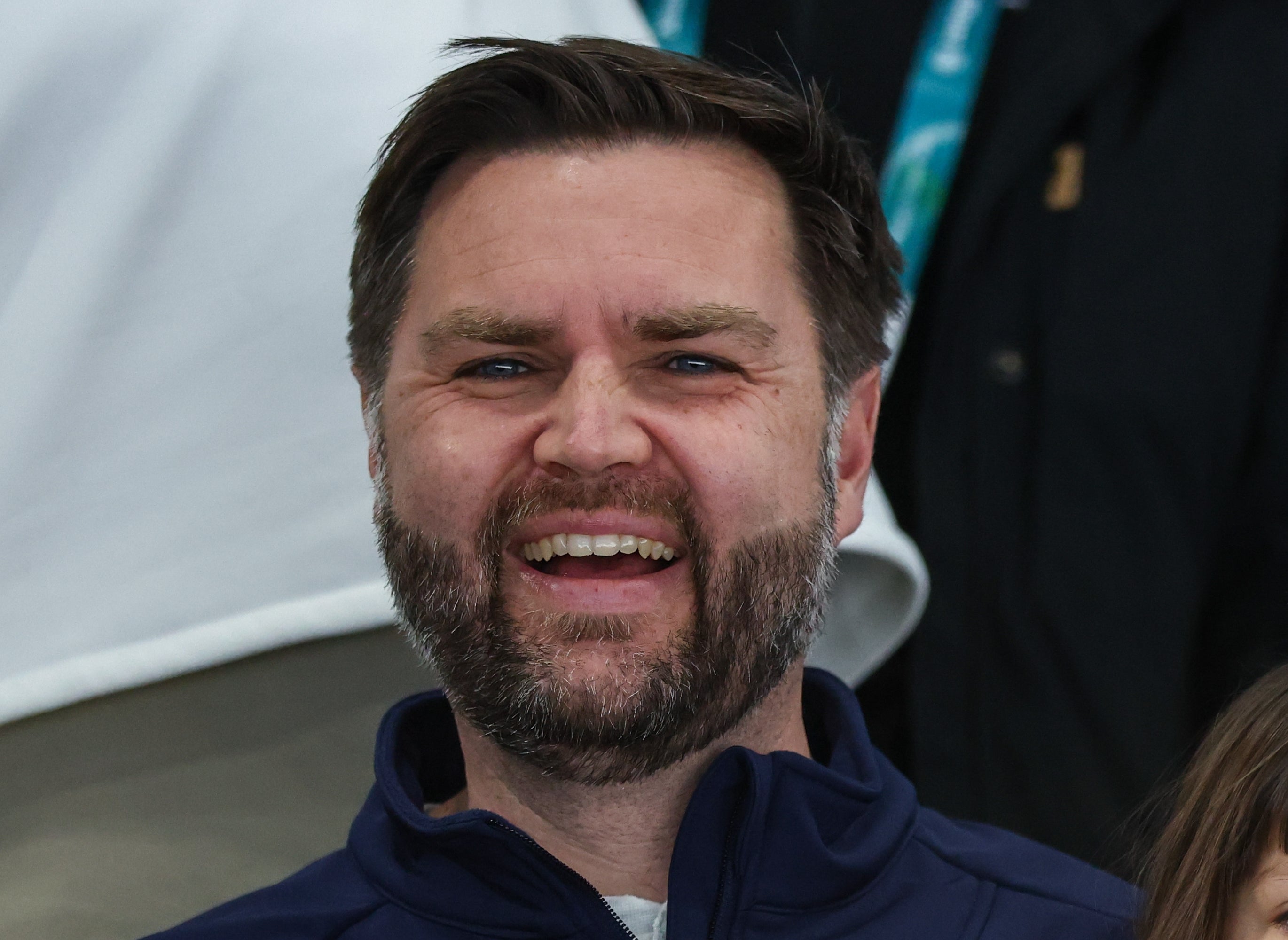 Man smiling, sitting with a young child on his lap. He wears a jacket with a crest and "Vance" embroidered on it
