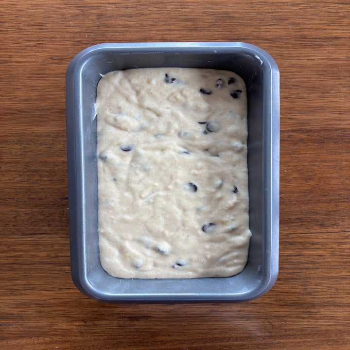 Batter with chocolate chips in a loaf pan on a wooden surface