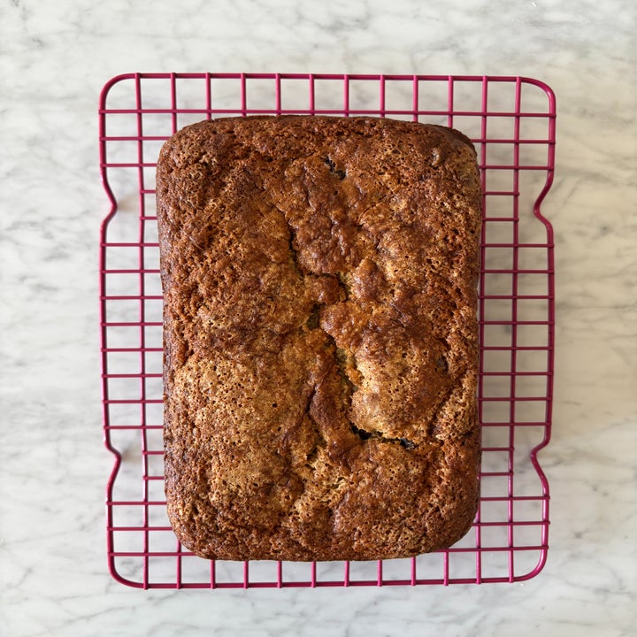 Loaf of banana bread cooling on a wire rack on a marble countertop
