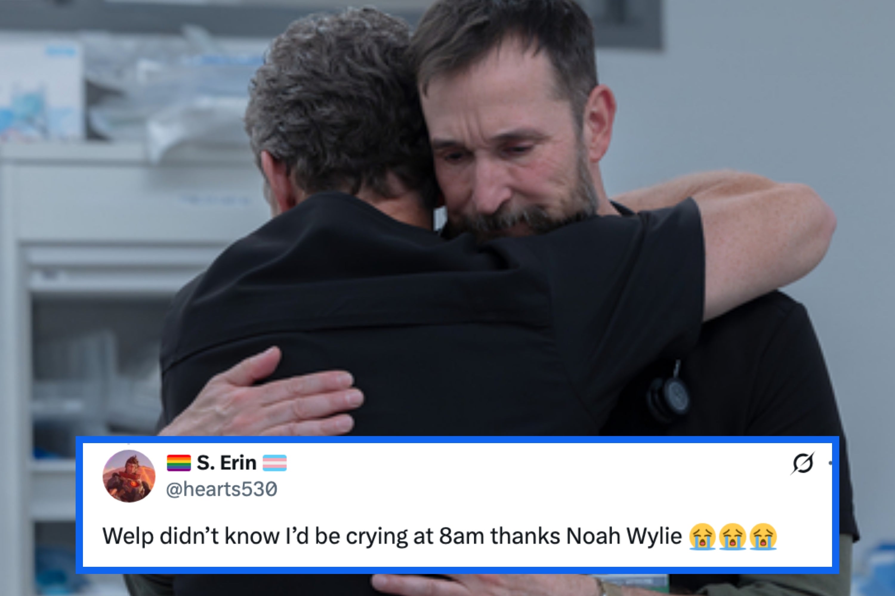 A man with a beard looks thoughtful while holding a baby wearing a hat indoors, with a decorative wall in the background