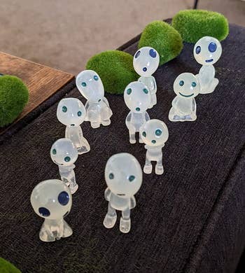 Small transparent figurines on a surface with mossy decorations