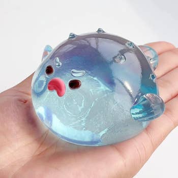 Translucent pufferfish stress ball with facial features held in hand, showcasing a playful and squeezable design