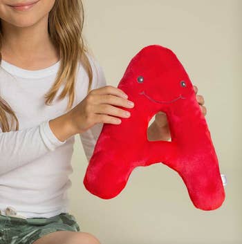 Child holding a plush red letter