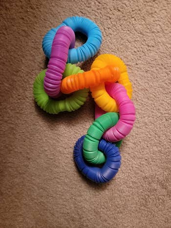Interlocking, textured fidget rings in various colors, placed on a carpet, ideal for sensory play or stress relief