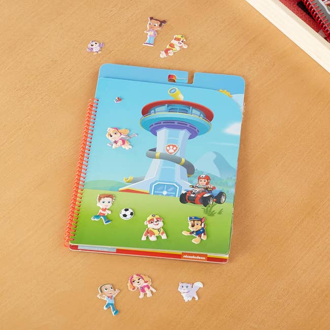 Notebook with cartoon characters from a popular animated series, featuring a tower and playful pups in action poses