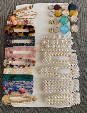 A display of various hair clips and pins featuring pearls, tortoiseshell, and colorful gemstones