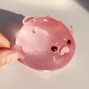 Squishy pink stress ball toy shaped like an angry pufferfish being squeezed and released