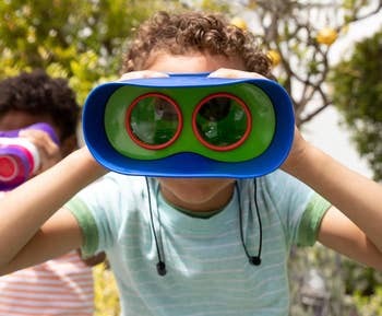 Child looking through colorful toy binoculars outdoors
