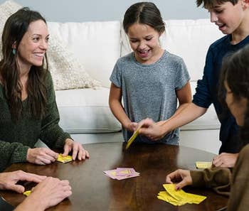 Family playing a card game at a wooden table with smiles and laughter