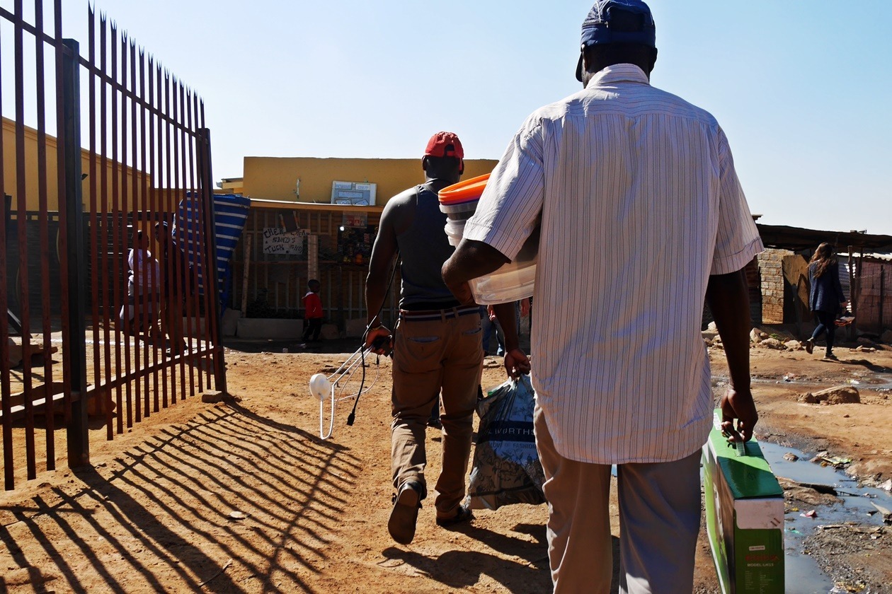 Männer tragen Fernseher und Antenne nach Hause in Soweto. Aufgenommen auf einer Fahrradtour mit Lebo´s Backpackers