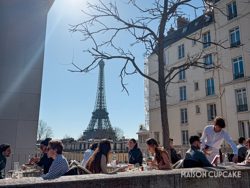 Parisian outdoor restaurant terrace with Eiffel Tower behind.