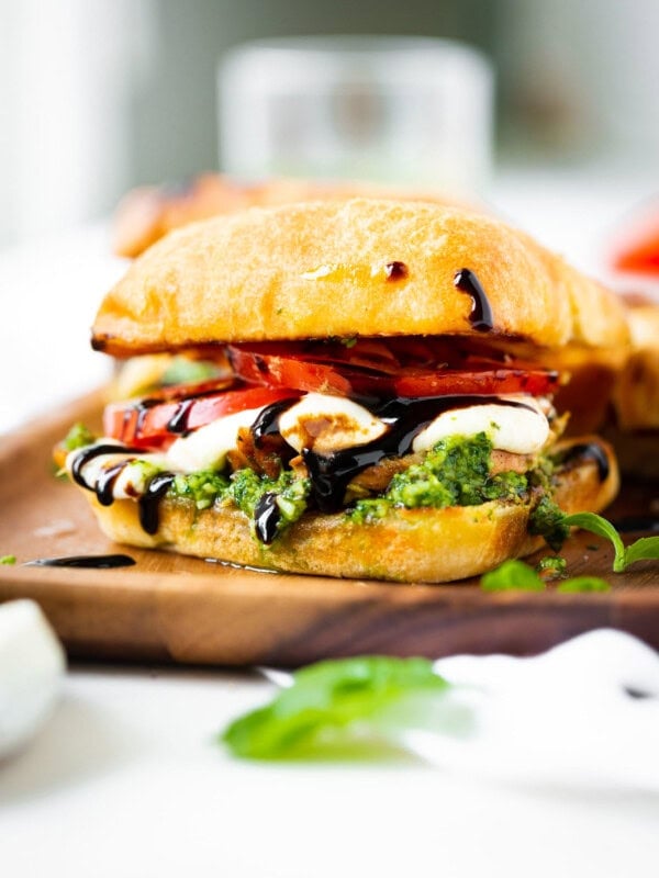 a photo of a chicken caprese sandwich on a ciabatta bun with tomato, fresh mozzarella, pesto and balsamic glaze.