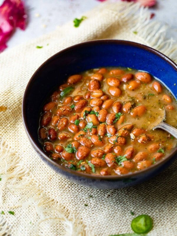 a photo of a royal blue ceramic bowl full of pinto beans topped with chopped fresh cilantro.