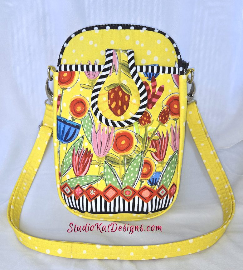 A yellow purse with strawberries and flowers on it.