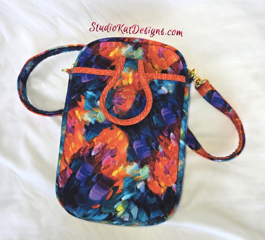 Small floral crossbody bag with vibrant colors and adjustable strap.