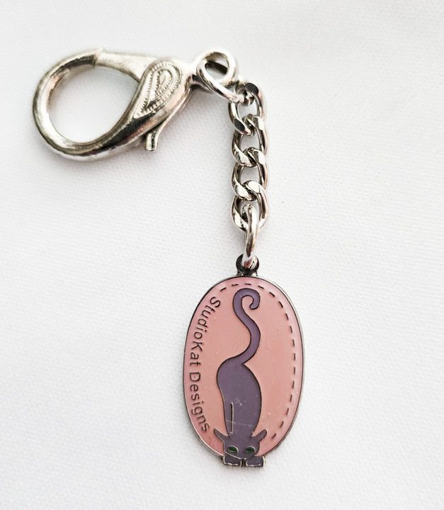 Oval keychain with a black cat silhouette and text.